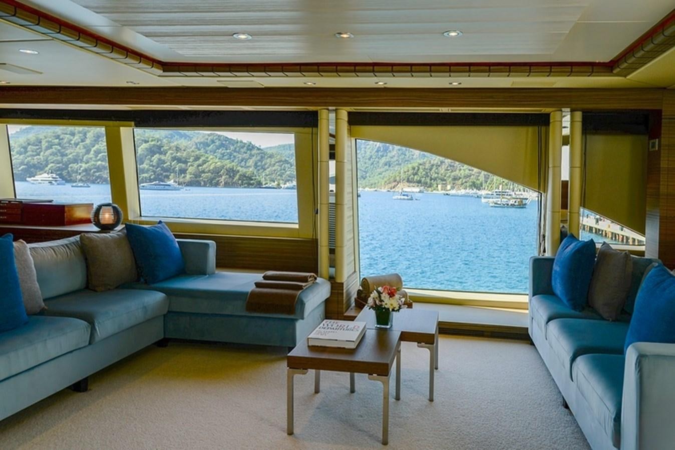 a living room with a blue couch and a large window aboard ORYX Yacht for Sale