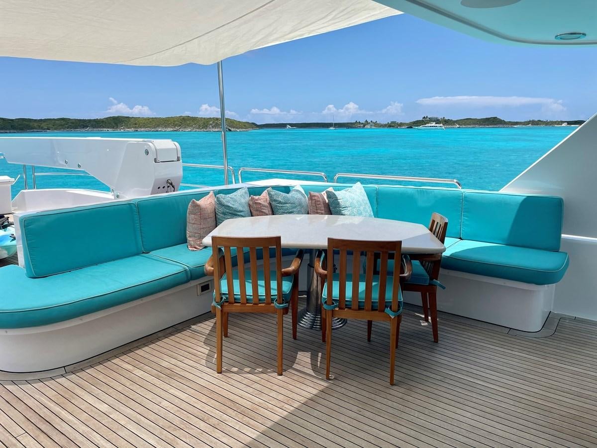 a table and chairs on a deck overlooking a body of water aboard RELENTLESS Yacht for Sale