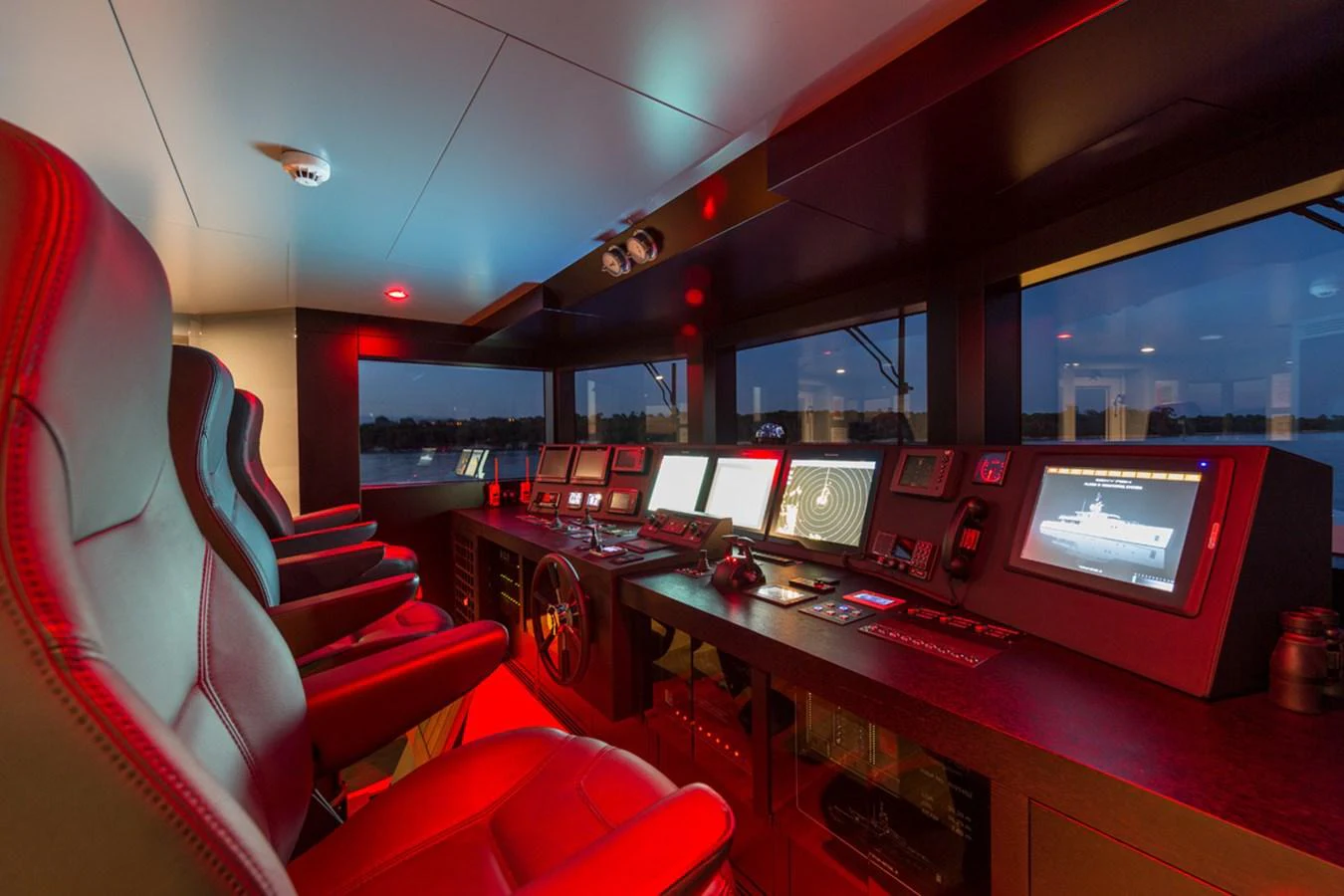 a room with red seats and a desk with computers on it aboard S7 Yacht for Sale