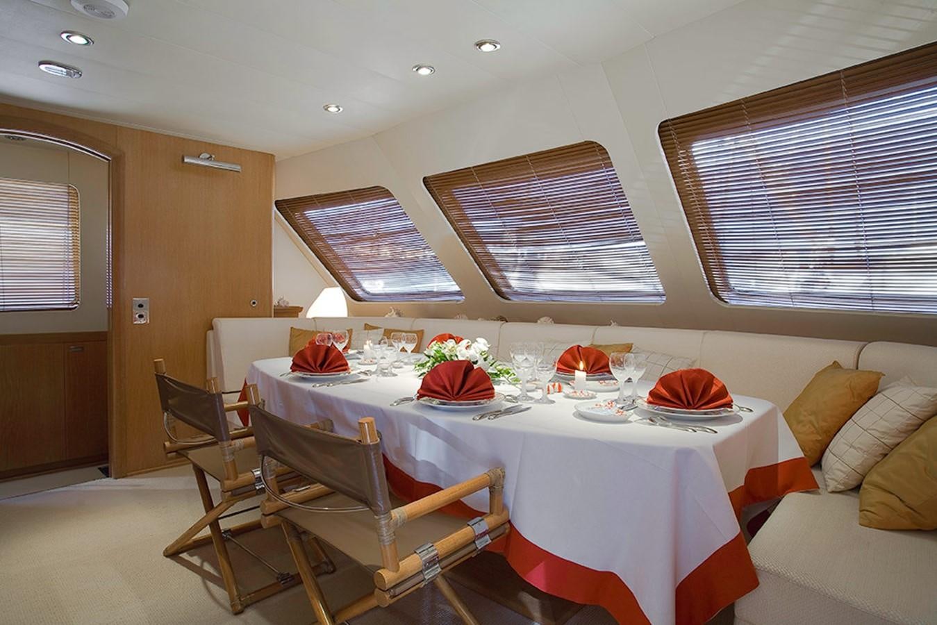a dining table with a white tablecloth and chairs aboard ALTHEA Yacht for Sale