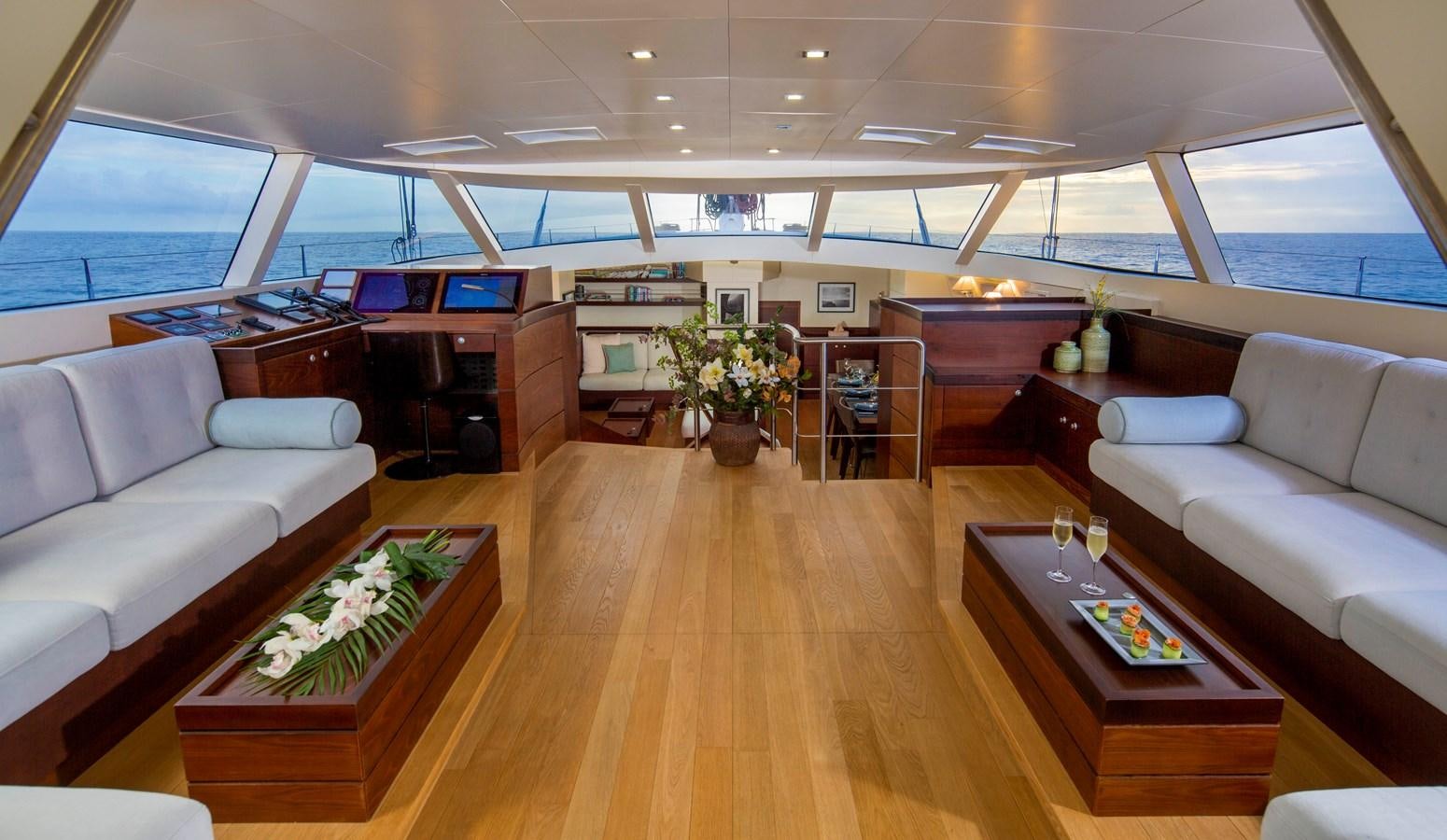 a room with a wood floor and white couches aboard RADIANCE Yacht for Sale