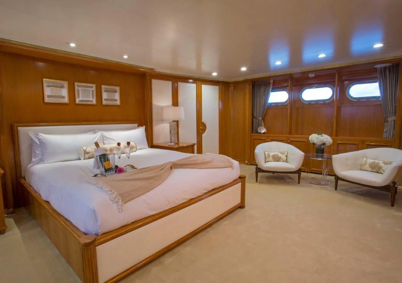 a large bedroom with a bed and a chair aboard LADY VICTORIA Yacht for Sale