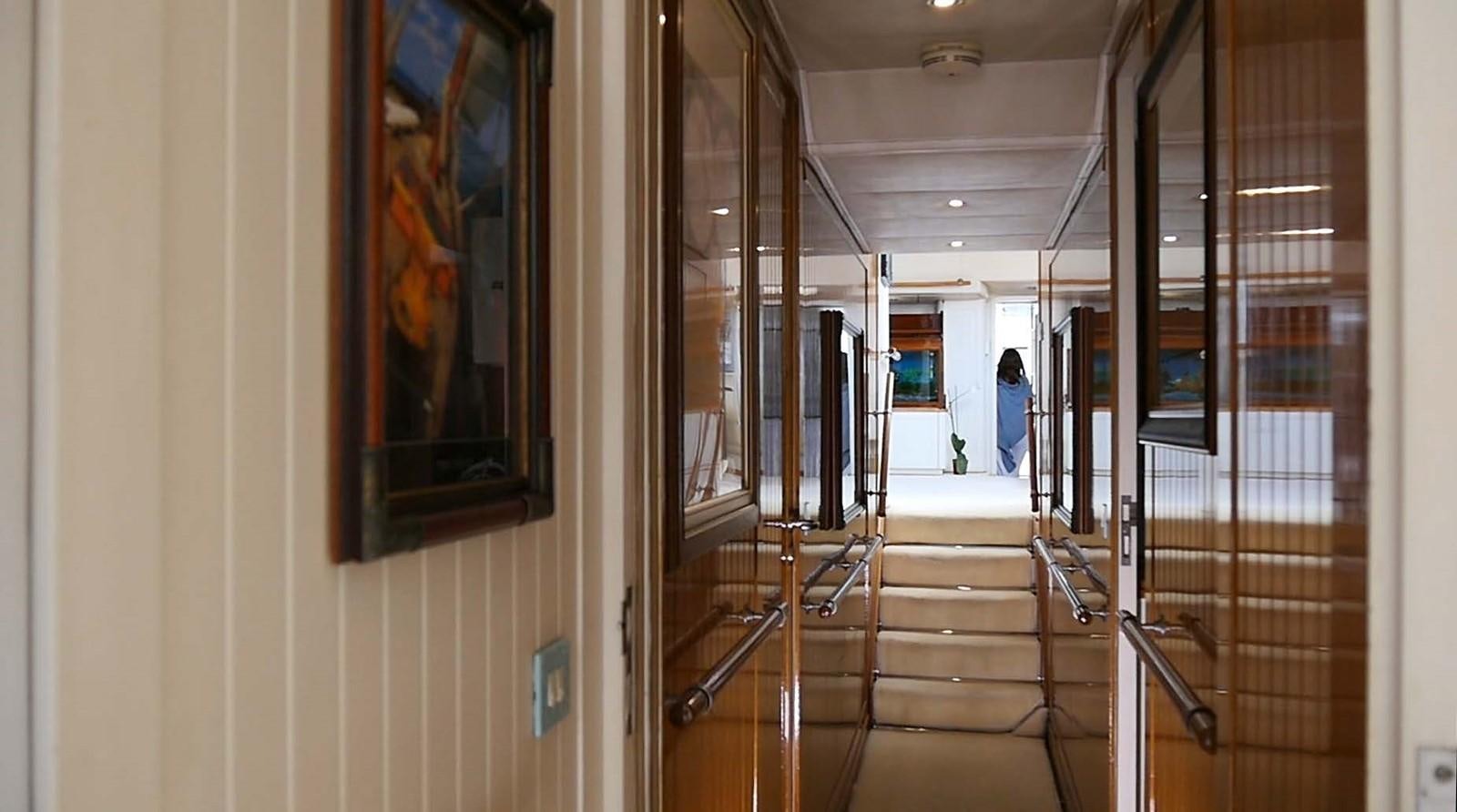 a hallway with a person walking on the stairs aboard INGENIOUS Yacht for Sale