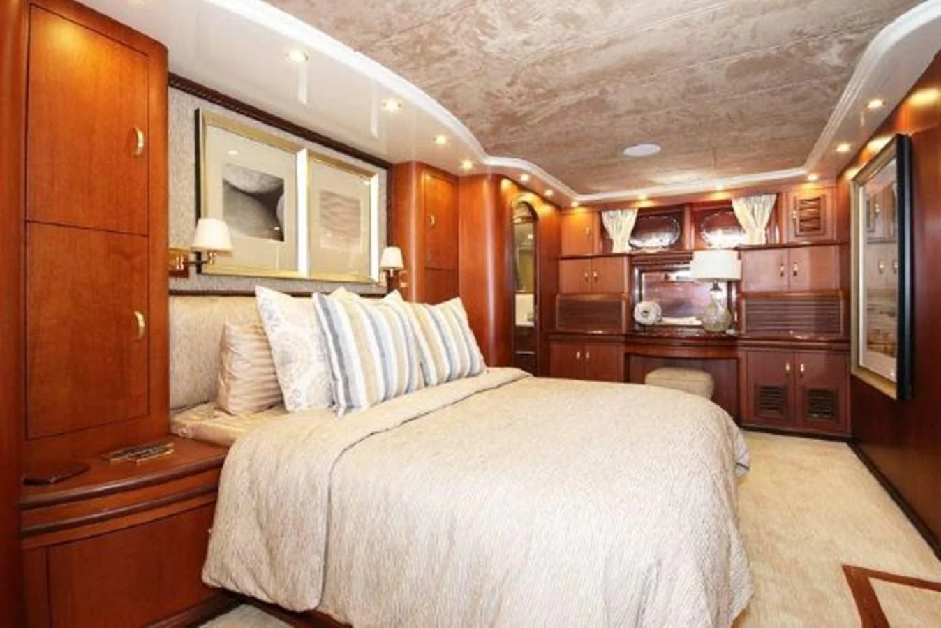 a bedroom with a bed and a wood cabinet aboard AMADEUS Yacht for Sale