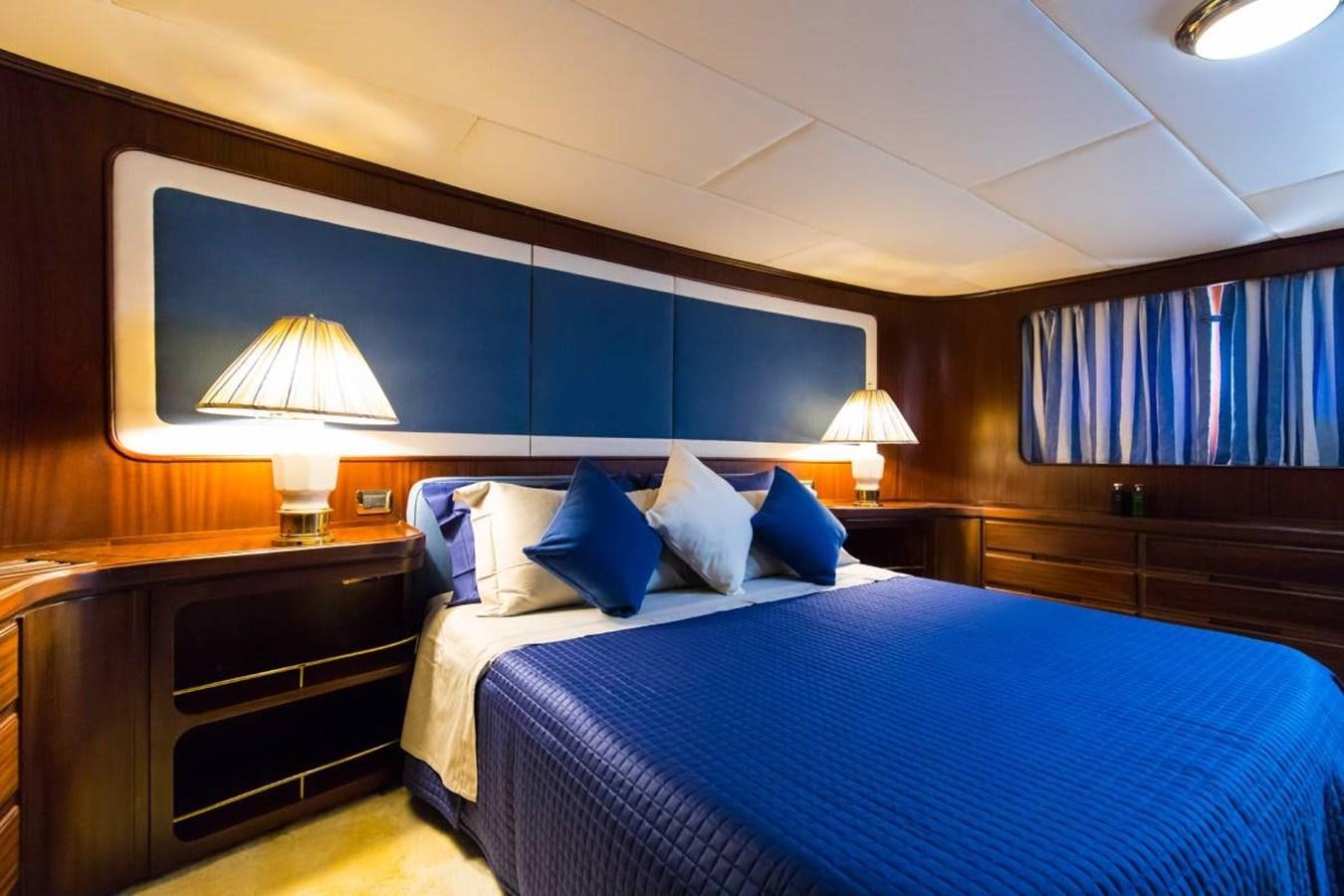 a bed with blue pillows aboard INDIA Yacht for Sale