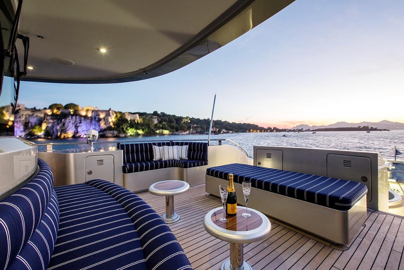 a balcony with a table and a glass of wine on the patio aboard PRINCESS ILUKA Yacht for Sale