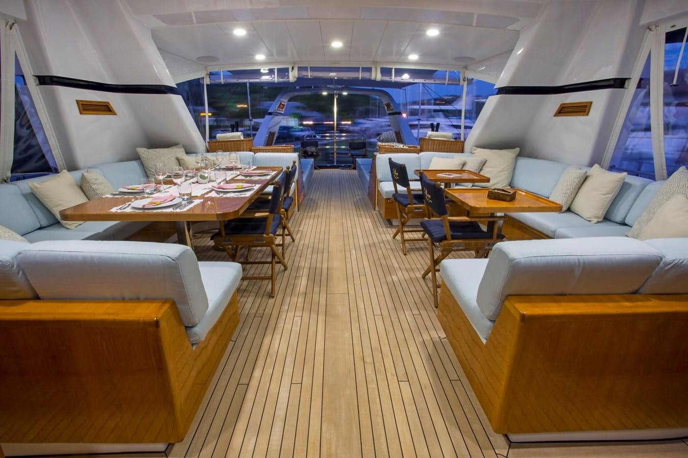 a room with a table chairs and a boat in the water aboard REE Yacht for Charter
