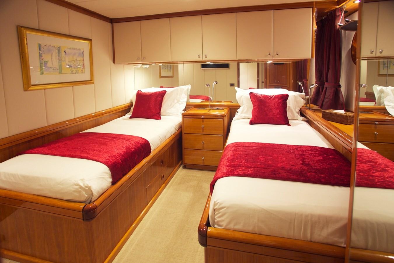 a room with beds and a dresser aboard REE Yacht for Charter