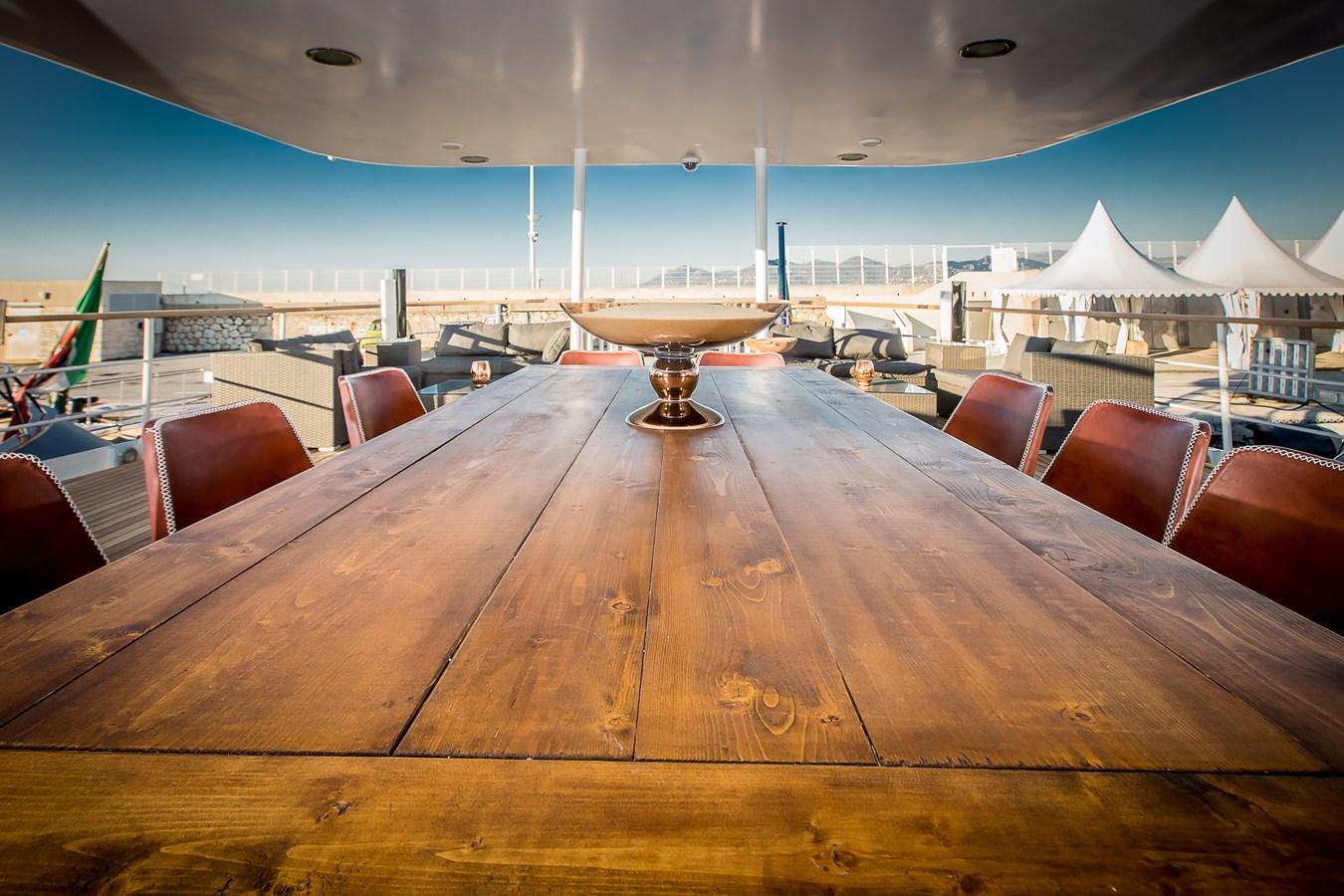 a wooden table with chairs and a large metal object on top aboard ALTER EGO Yacht for Sale