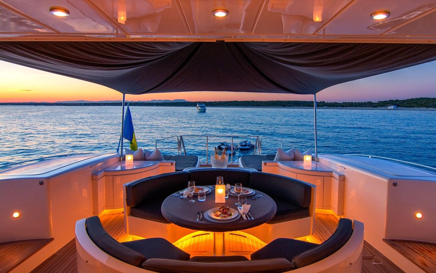 a table with candles on it in front of a large body of water aboard LE MAGNIFIQUE Yacht for Sale