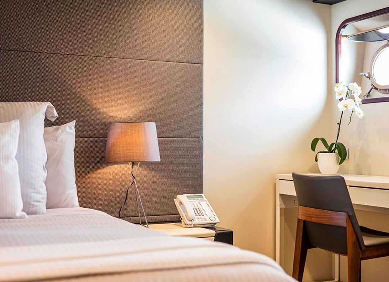 a hotel room with a bed and a desk aboard CORROBOREE Yacht for Sale