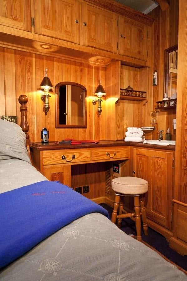 a wooden cabin with a bed and desk aboard TIGERLILY OF CORNWALL Yacht for Sale