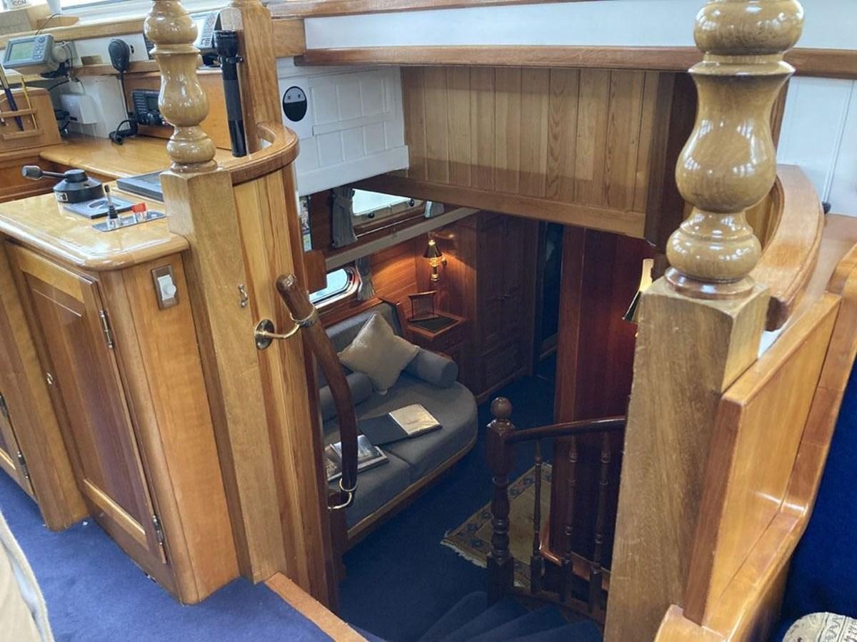 a wooden cabinet with a chair and a table with a chair aboard TIGERLILY OF CORNWALL Yacht for Sale