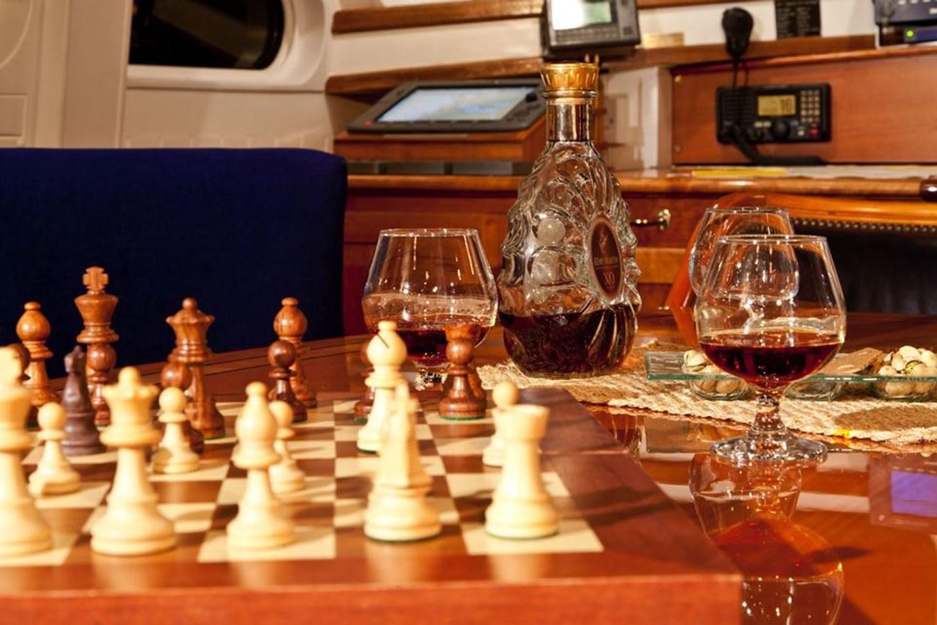 a table with a glass and a chess board and a chessboard aboard TIGERLILY OF CORNWALL Yacht for Sale