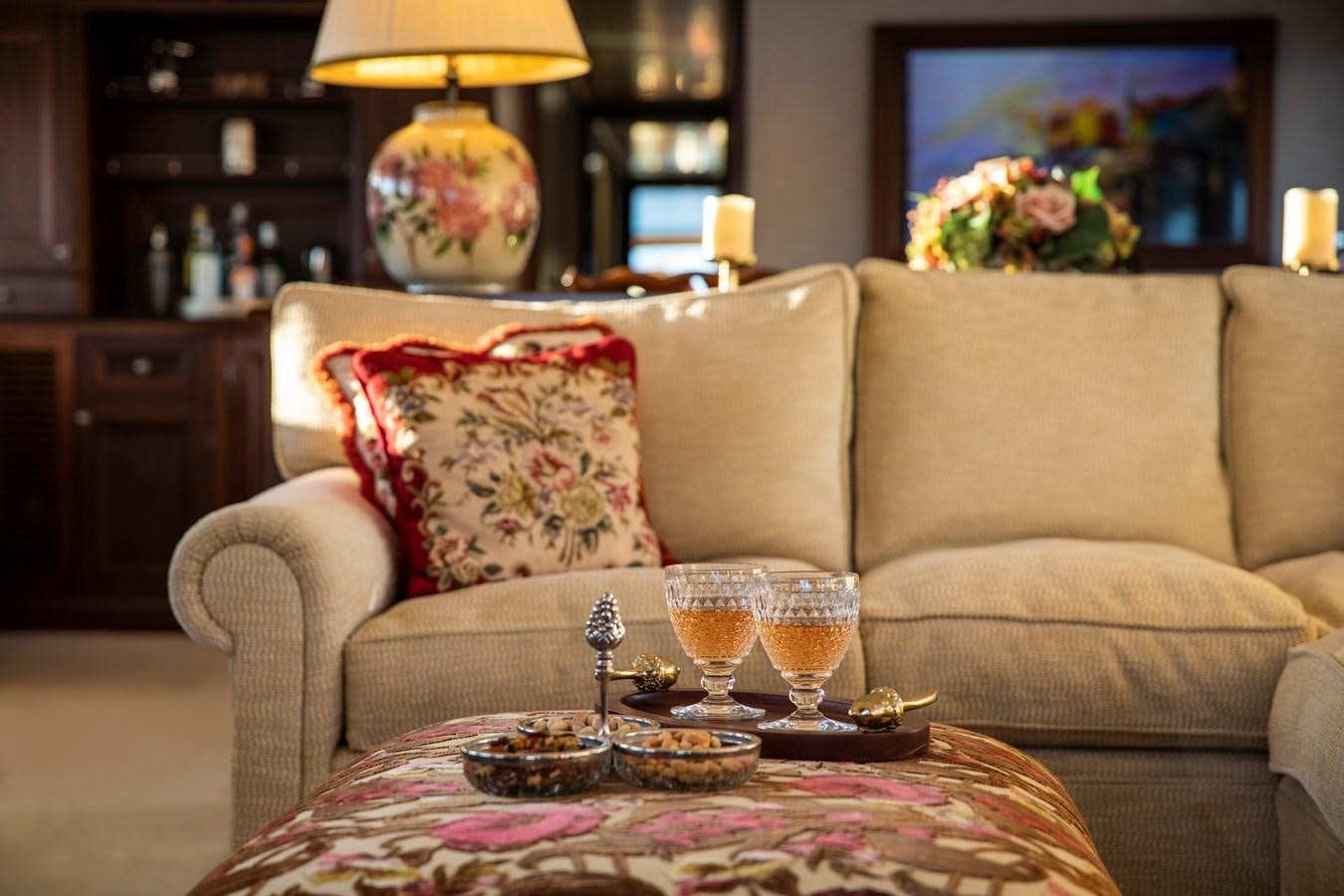 a couch with a glass of wine and a table with food on it aboard ODYSSEY III Yacht for Charter