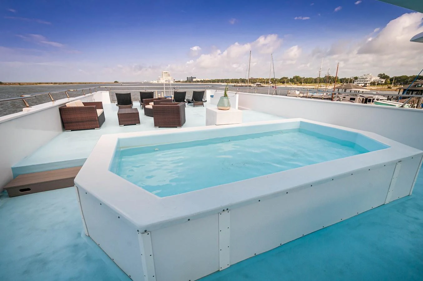a pool with a deck and a building in the background aboard LE COLBY JEAN Yacht for Sale