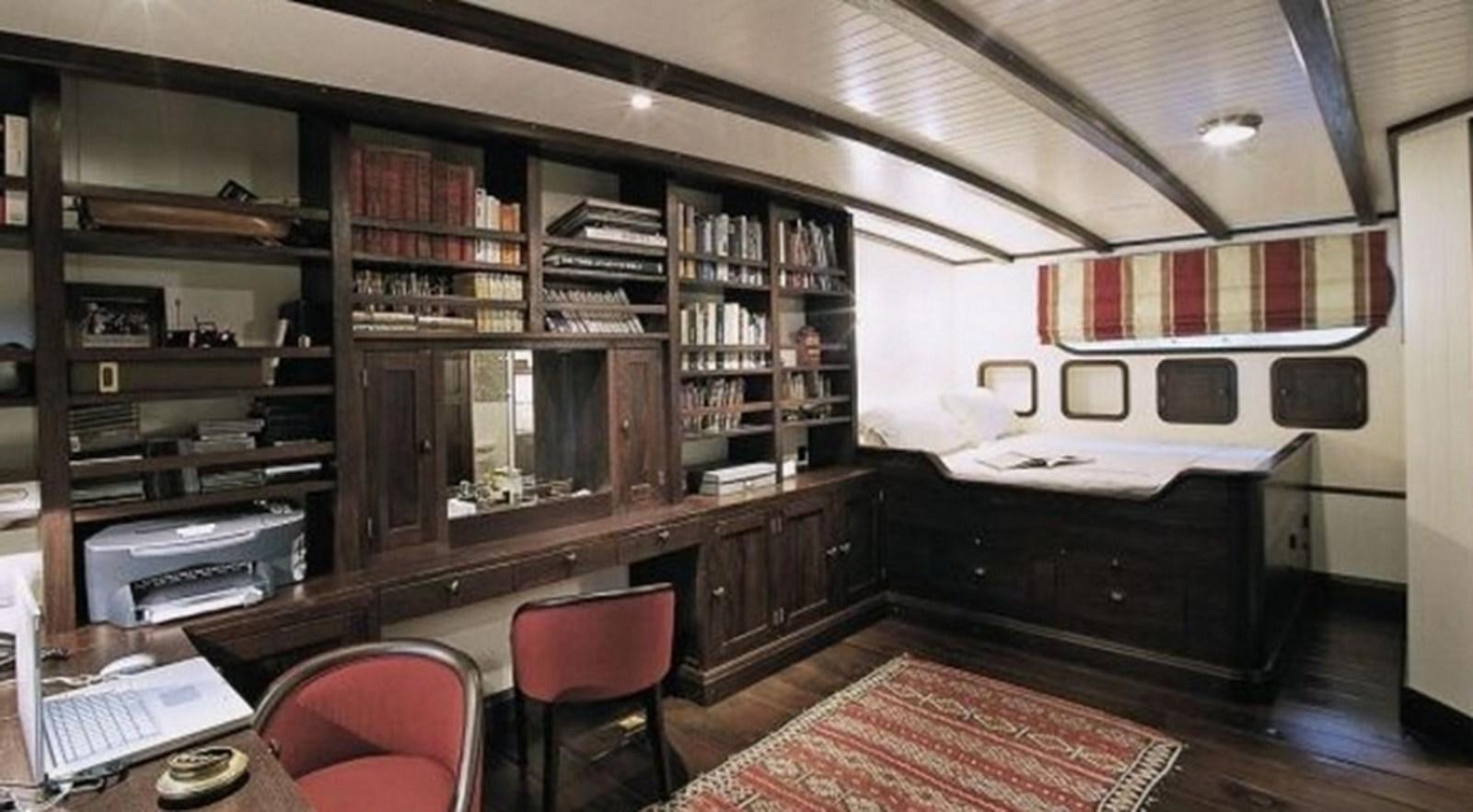 a room with a bed desk and shelves aboard ABELY Yacht for Charter