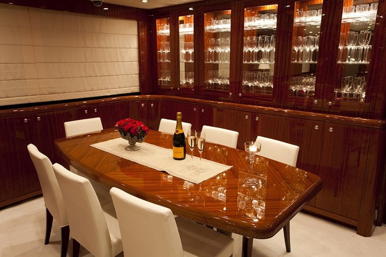 a table with wine glasses and a bottle on it aboard QUEEN GRACE Yacht for Sale