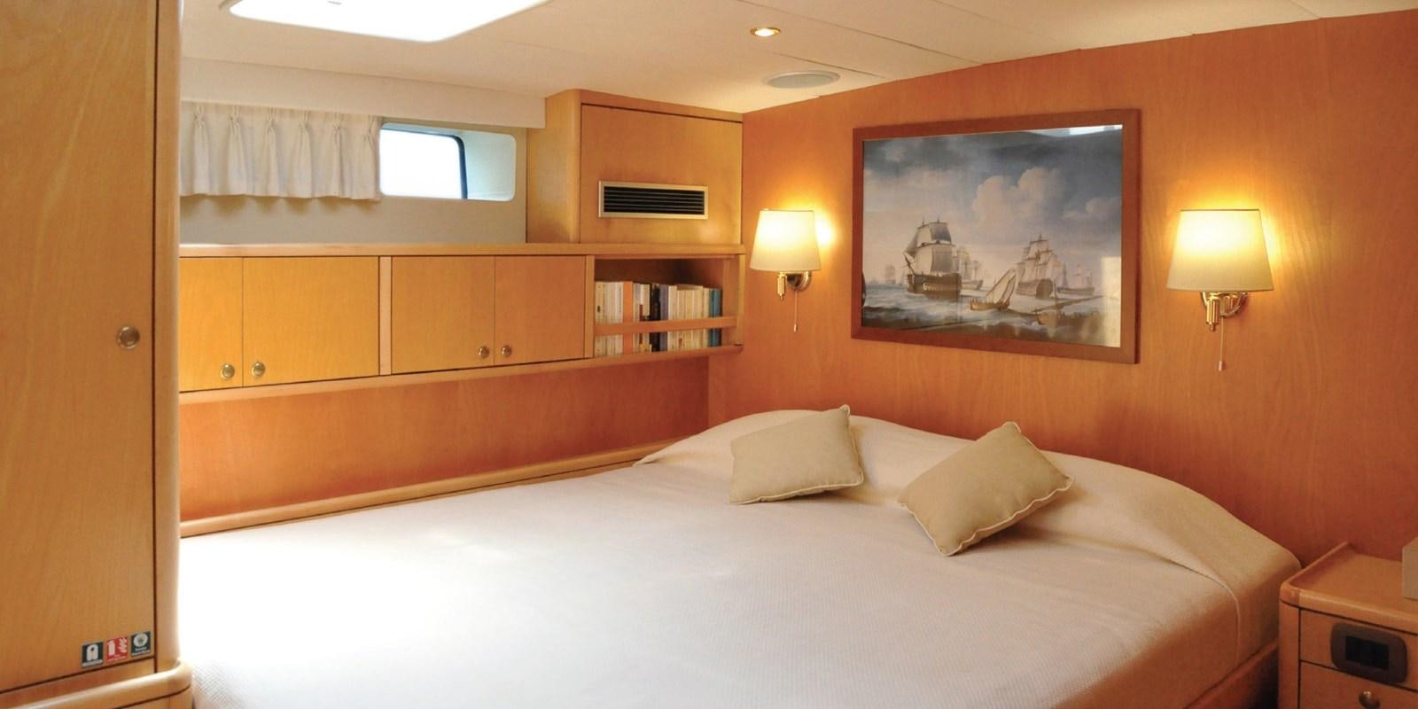 a bed with a white sheet and pillows in a room with a wood cabinet and a window aboard ASAHI Yacht for Sale