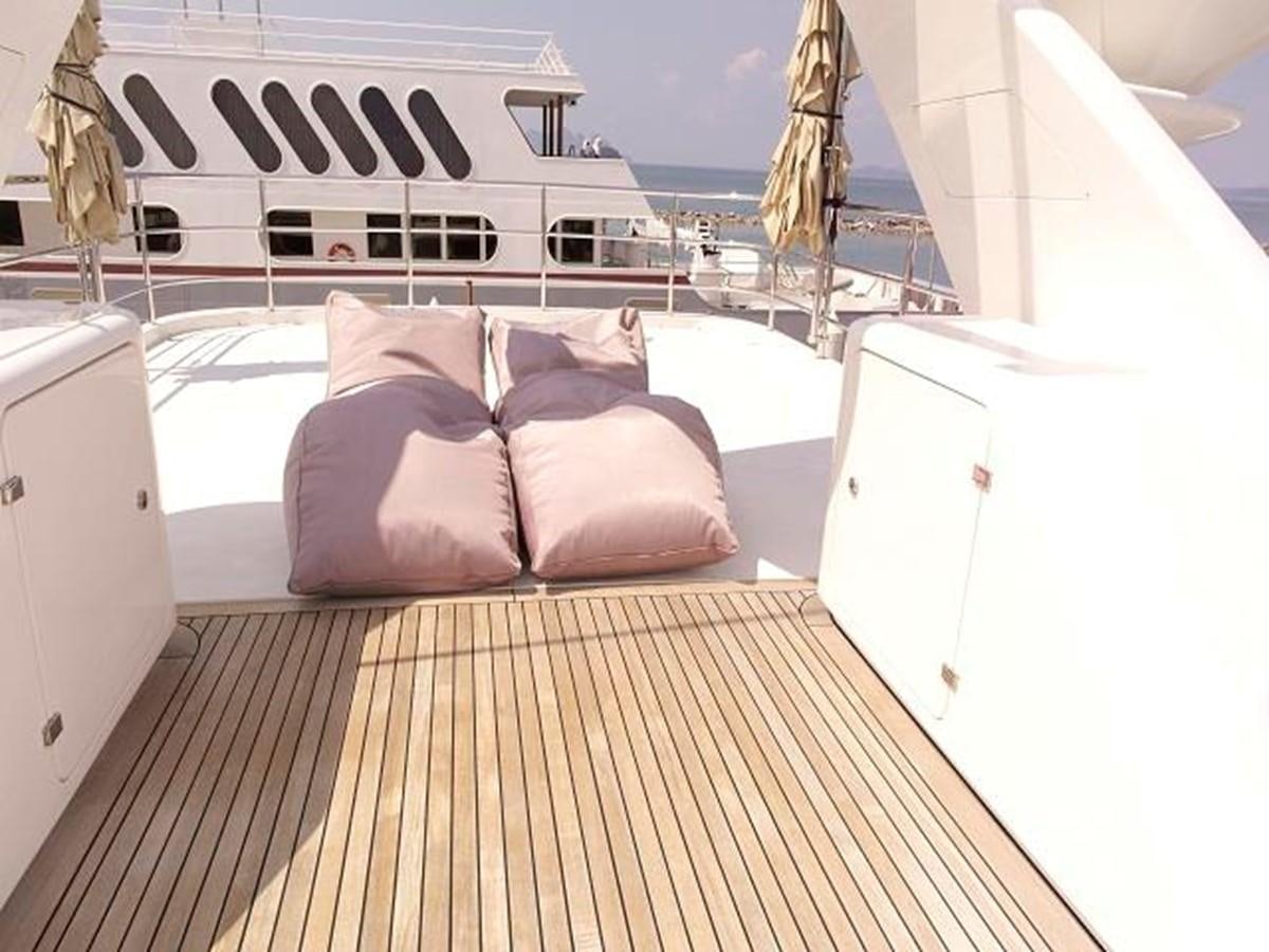 a bed with pillows and a white building in the background aboard BENETTI TRADITION 100 Yacht for Sale