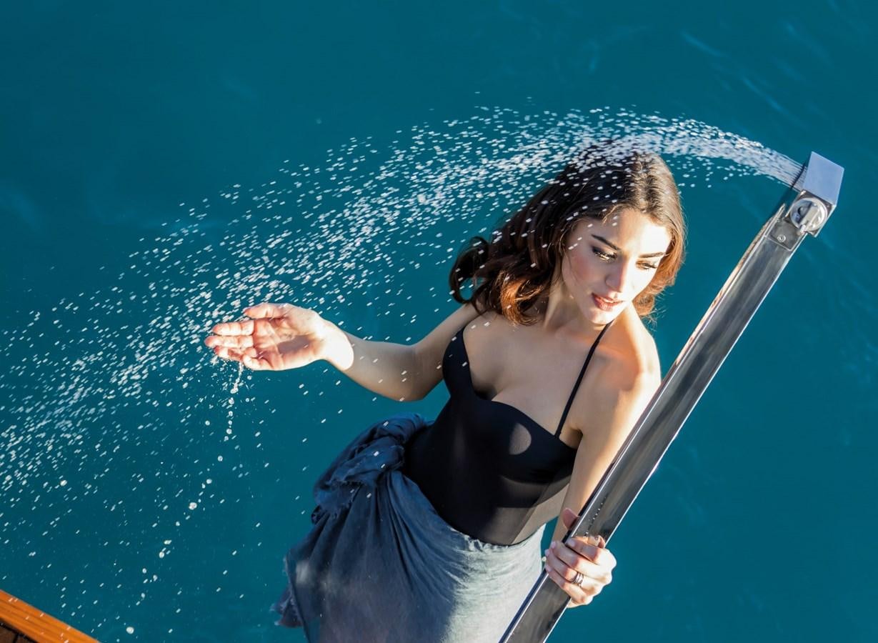 a person in a black dress holding a paddle in a pool aboard BESO Yacht for Sale