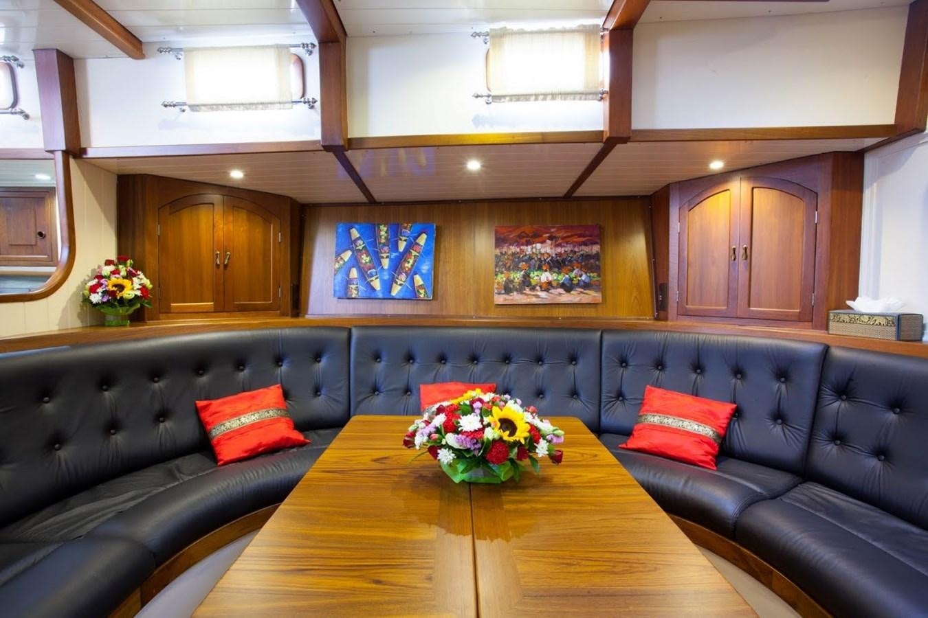 a room with a couch and a table with flowers on it aboard DALLINGHOO Yacht for Sale