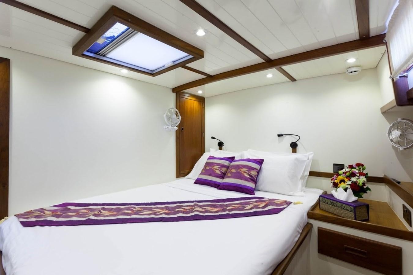 a bed with a purple and white blanket and a white pillow aboard DALLINGHOO Yacht for Sale