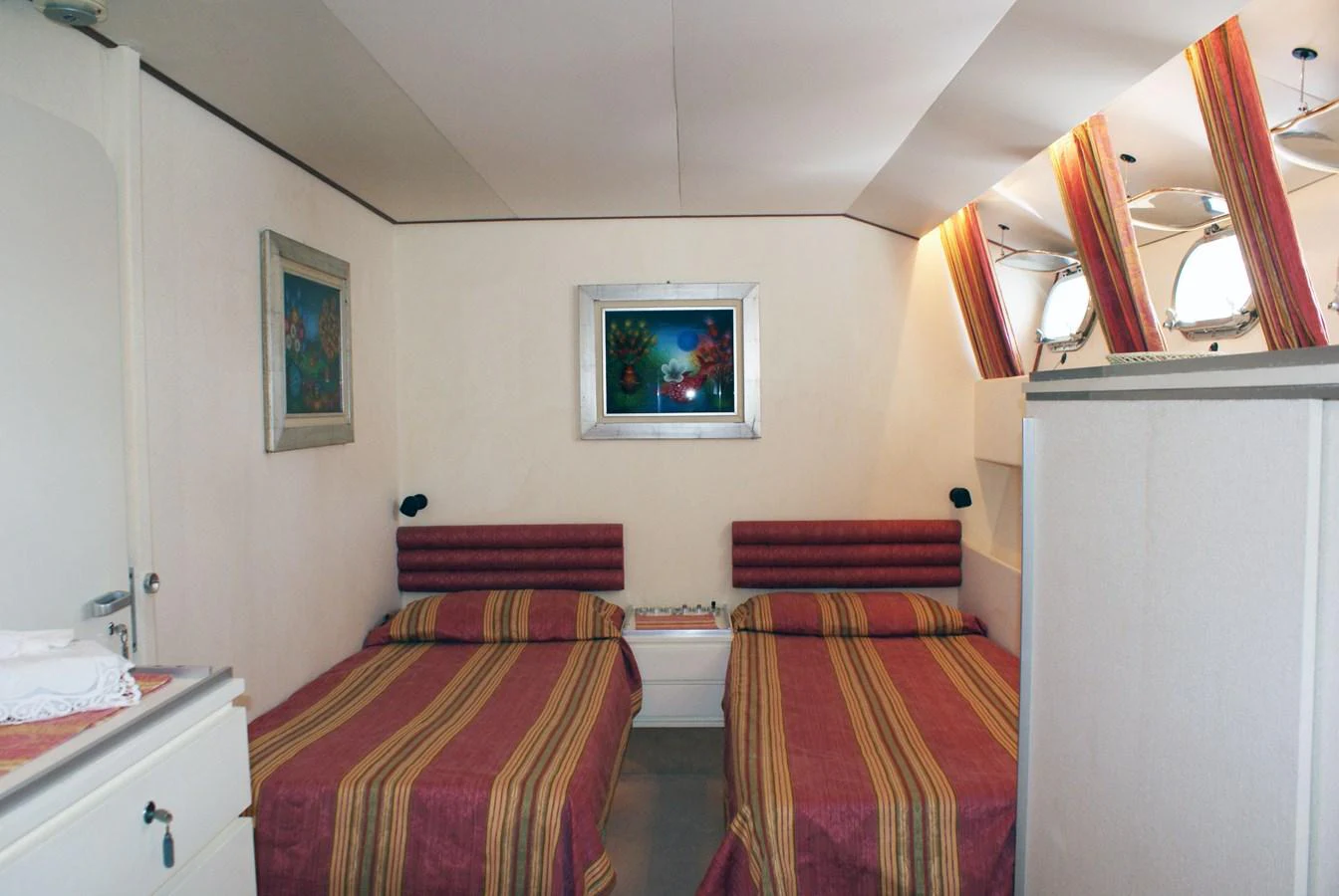 a bedroom with a bed and a painting on the wall aboard LUC AN Yacht for Sale