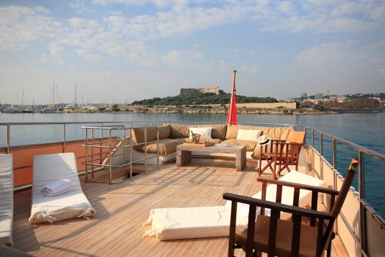 a deck with chairs and tables on it by a body of water aboard CONQUEST OF 1966 Yacht for Sale