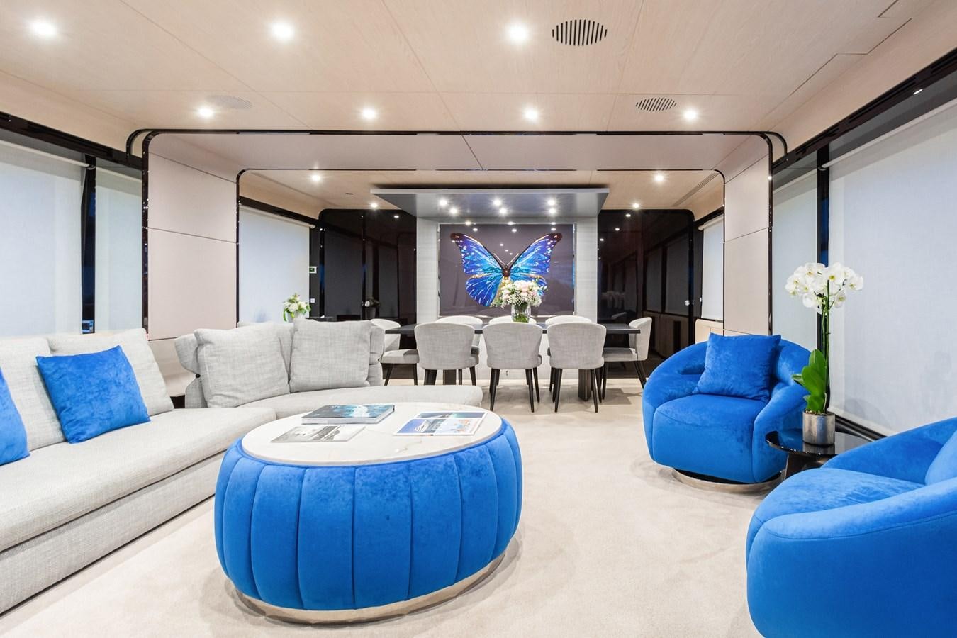 a large living room with a blue couch and a large blue table aboard SOLSTICE Yacht for Sale