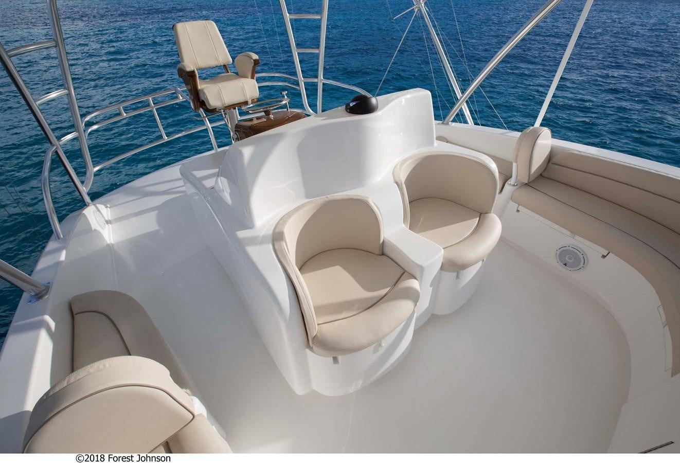 a boat with a chair on the deck aboard 2022 VIKING 92 ENCLOSED SKYBRIDGE (TBD) Yacht for Sale