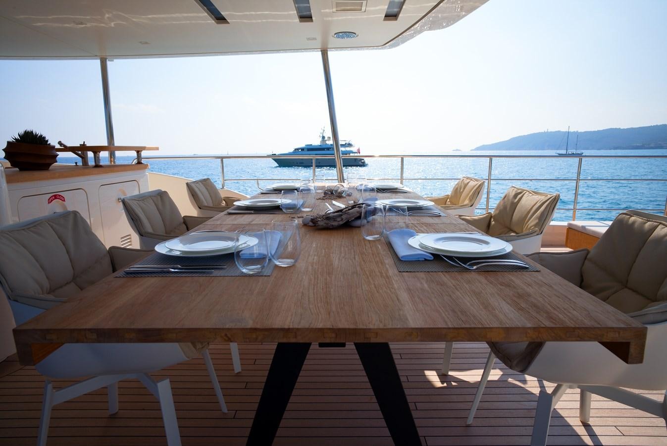 a table with chairs and a view of the ocean aboard ELMO Yacht for Sale