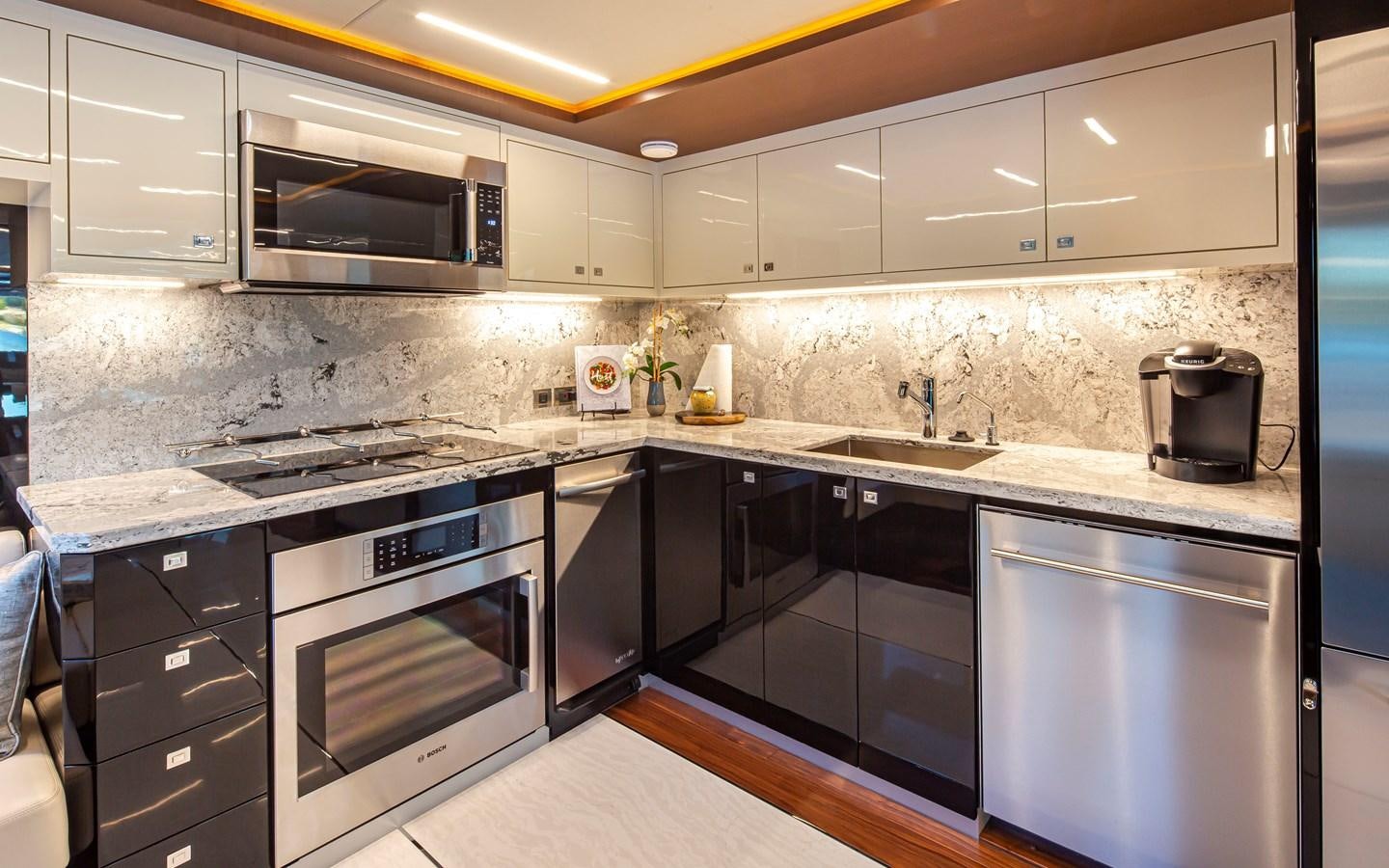 a kitchen with black appliances aboard 90R03 Yacht for Sale
