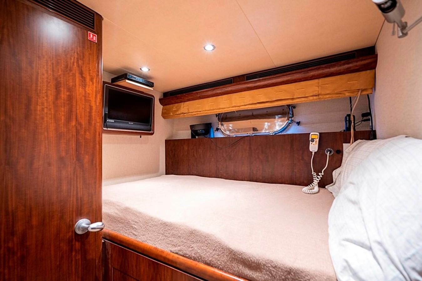 a bed with a television on the wall aboard GRAND LEGACY Yacht for Sale