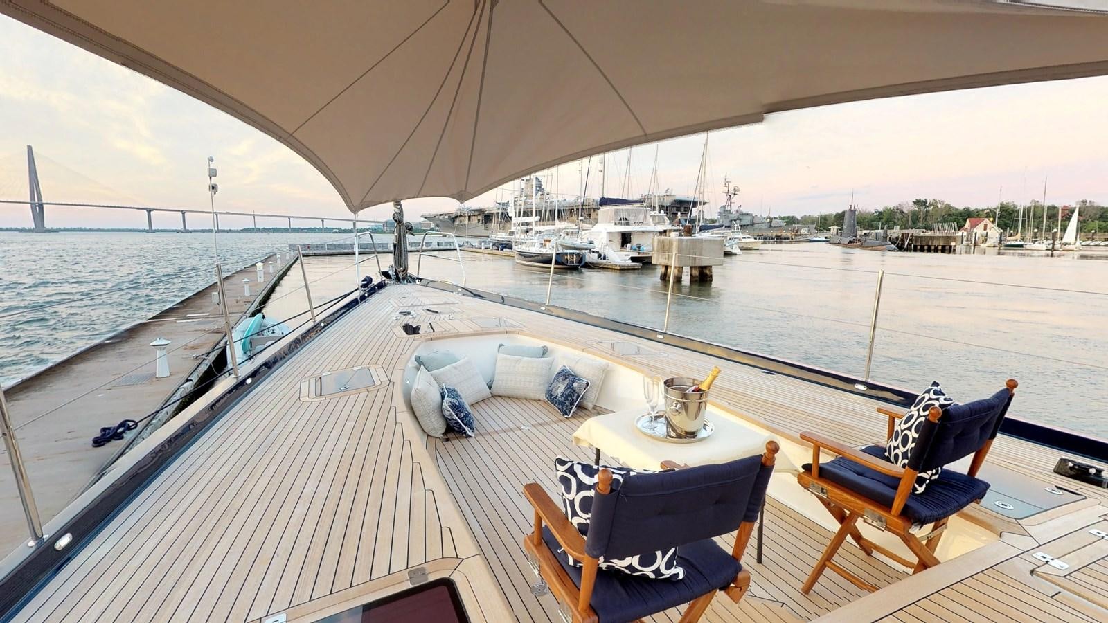 a deck with a table chairs and a view of the water aboard AYNI Yacht for Sale