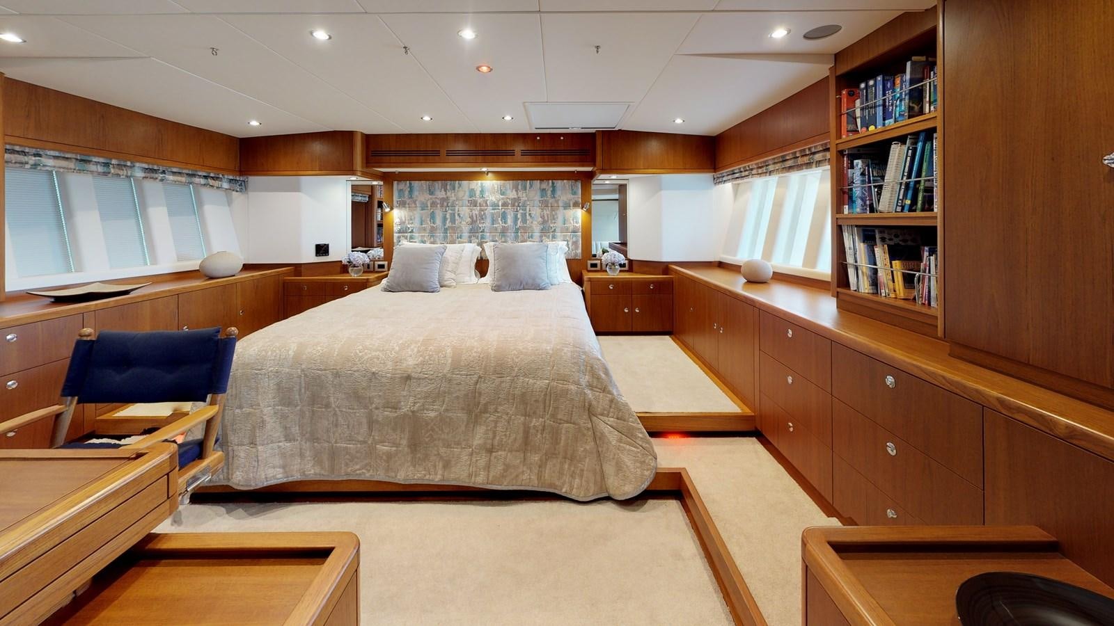 a room with a bed and a bookcase aboard AYNI Yacht for Sale