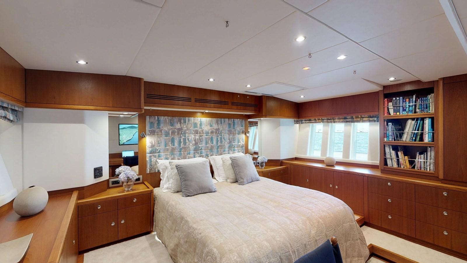 a bedroom with a bed and a bookcase aboard AYNI Yacht for Sale