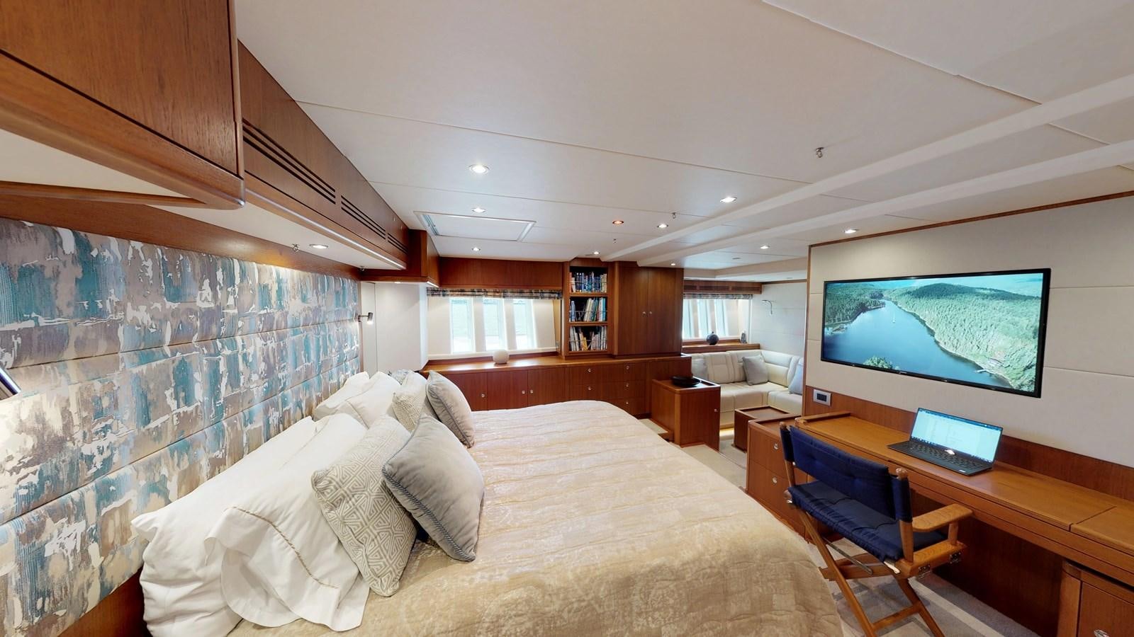a bedroom with a large bed and a tv on the wall aboard AYNI Yacht for Sale
