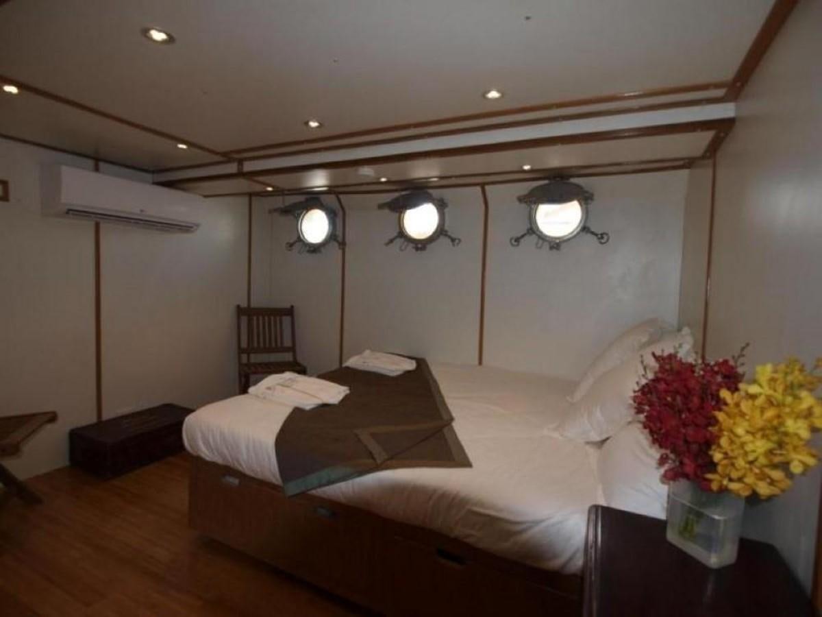 a bedroom with a bed and a table aboard KAMA BAY Yacht for Sale