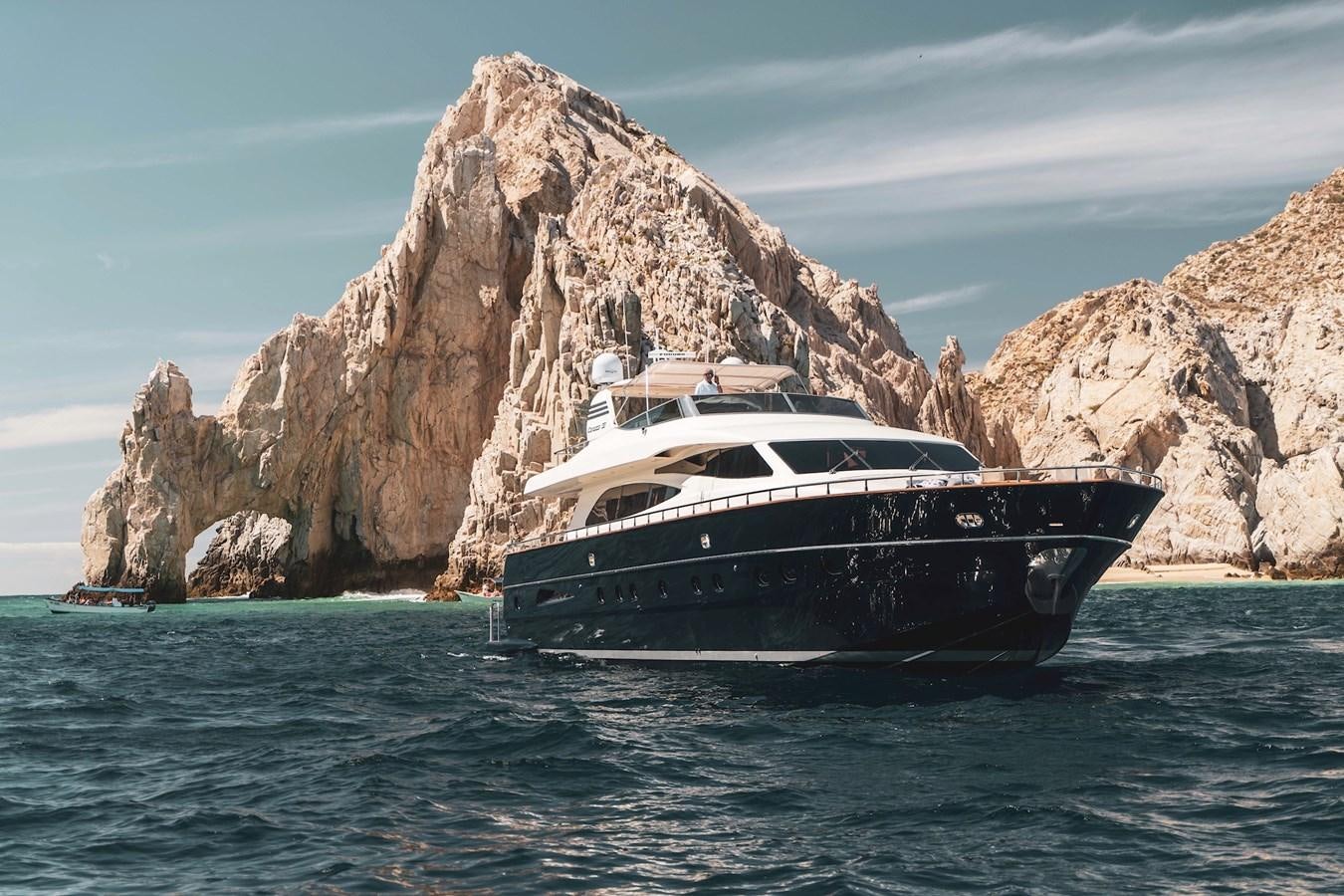 a boat in the water with Arch of Cabo San Lucas in the background aboard CATARI Yacht for Sale