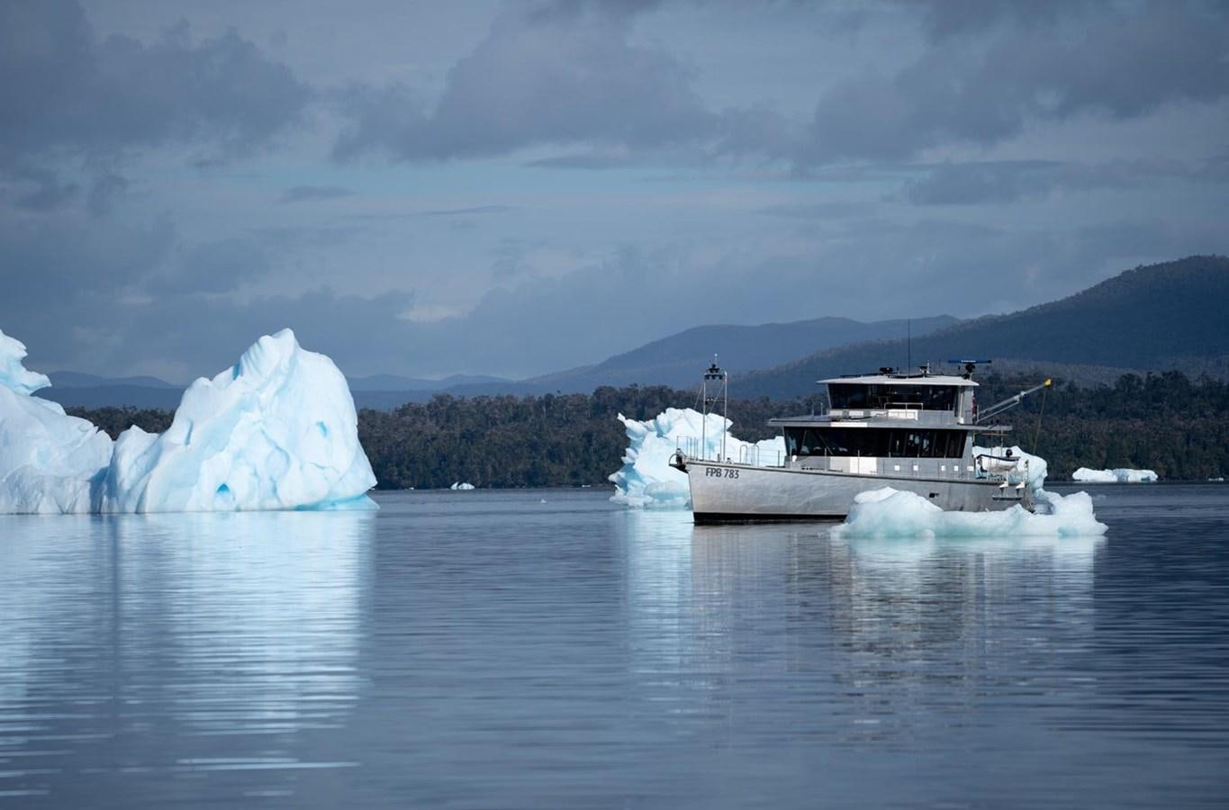 a boat on water with icebergs in the background aboard IRON LADY II Yacht for Sale