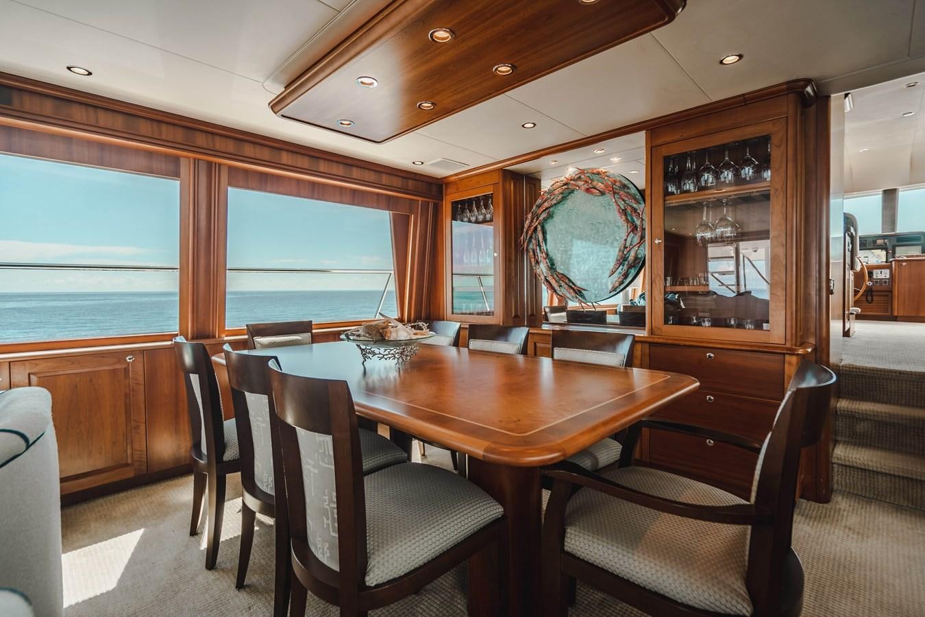 a dining table and chairs in a room with a large window aboard NOW OR NEVER Yacht for Sale