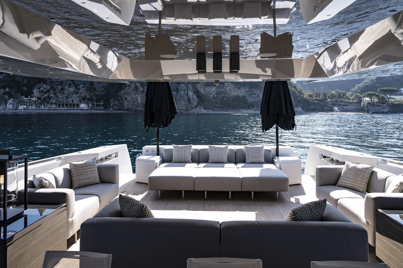 a lounge area with a large swimming pool and a large building with a view of the water and aboard ARCADIA A85 Yacht for Sale