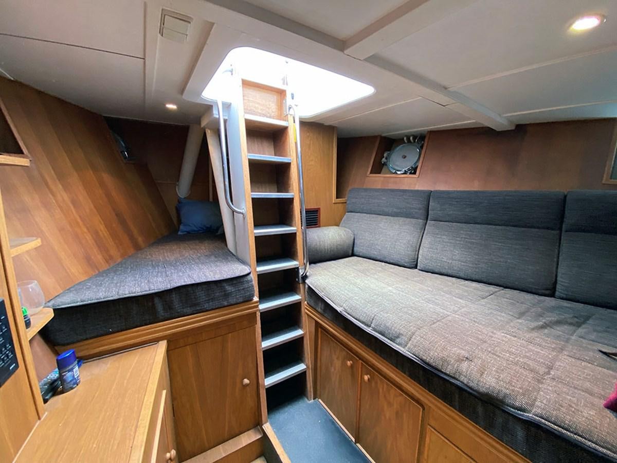 a living room with a bed and a ladder aboard COLUMBUS OF LYMINGTON Yacht for Sale