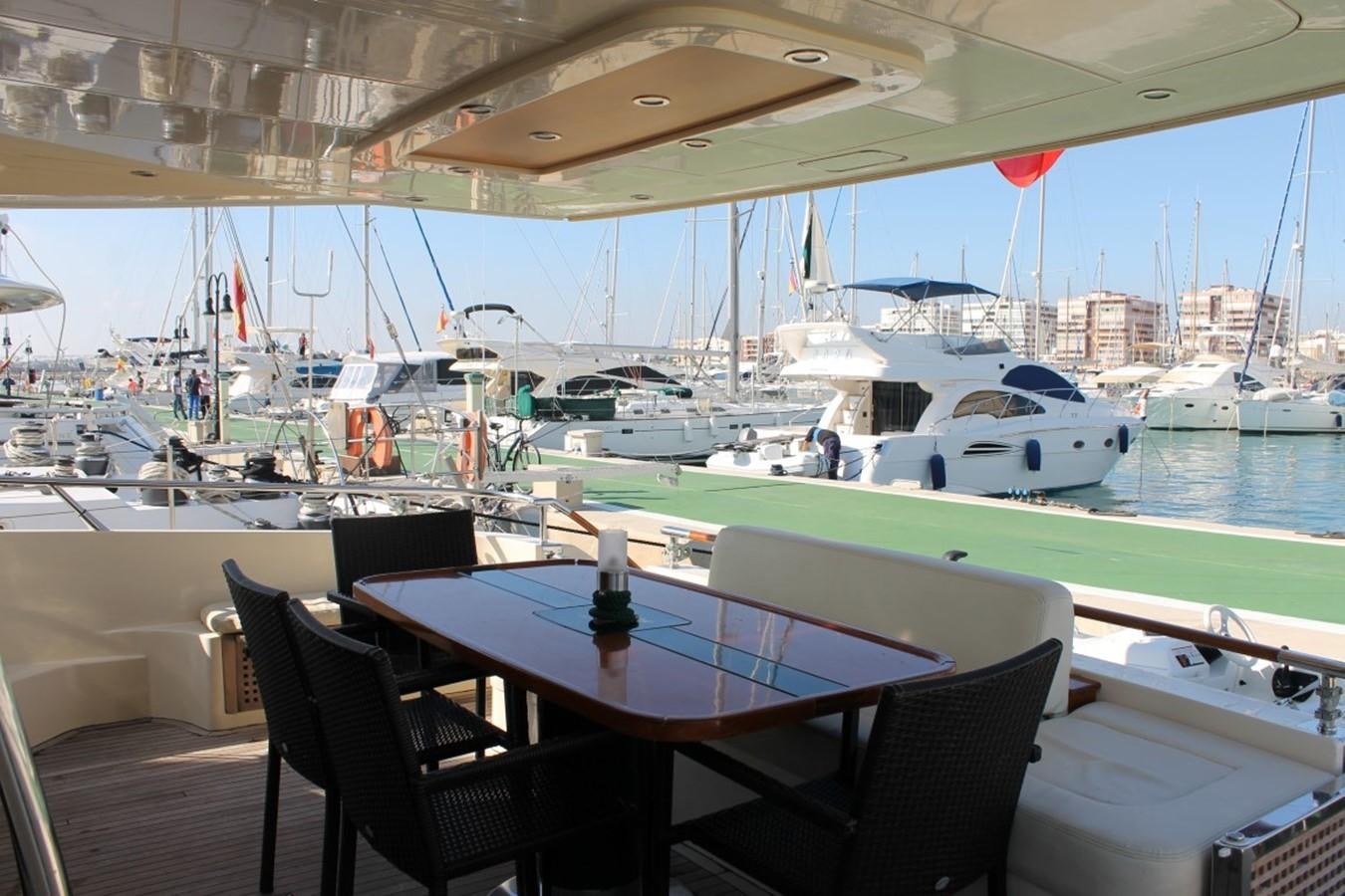 a table and chairs on a deck overlooking a marina with boats aboard MACAMI Yacht for Sale