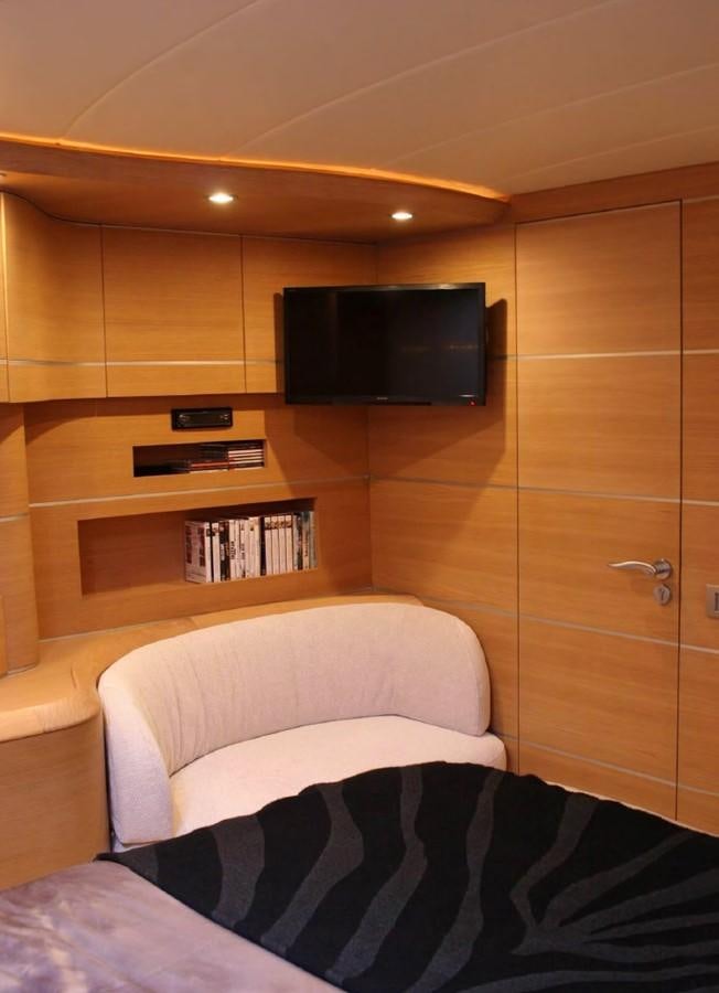 a room with a tv and a shelf with books aboard FOX Yacht for Sale