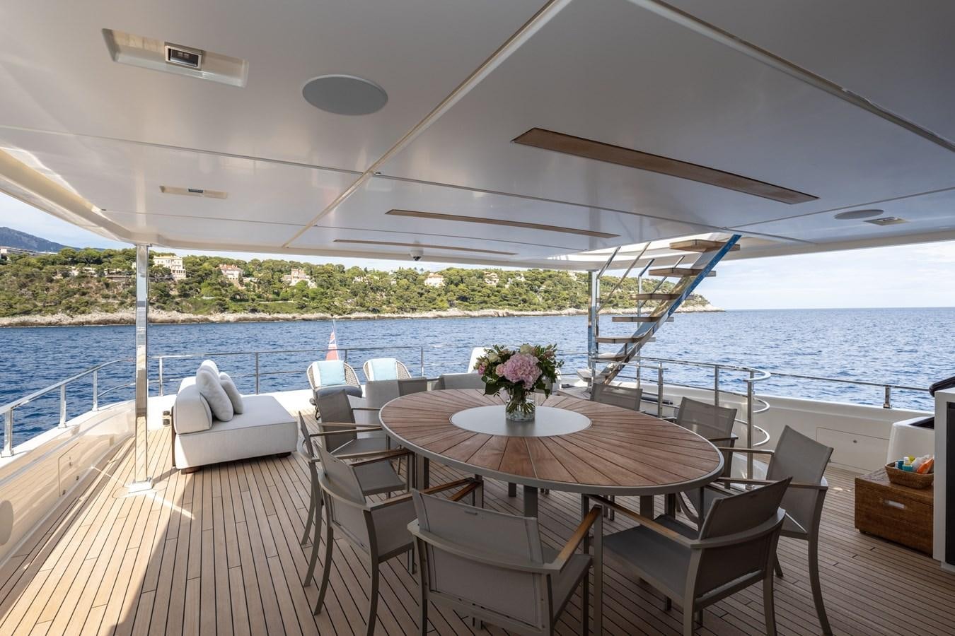 a table and chairs on a deck overlooking a body of water aboard EROS Yacht for Sale