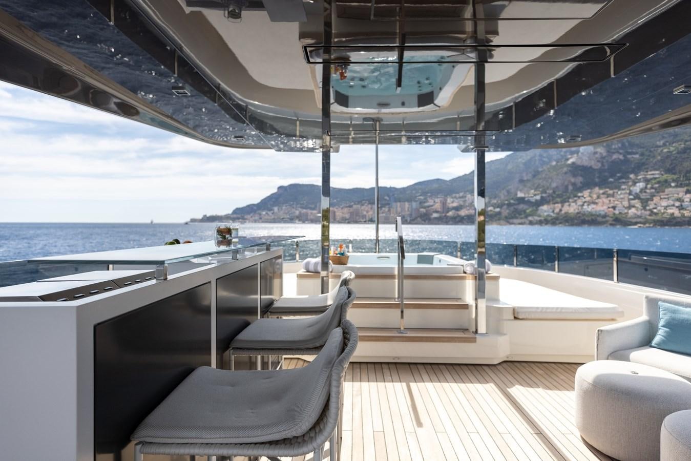 a deck with chairs and a body of water in the background aboard EROS Yacht for Sale