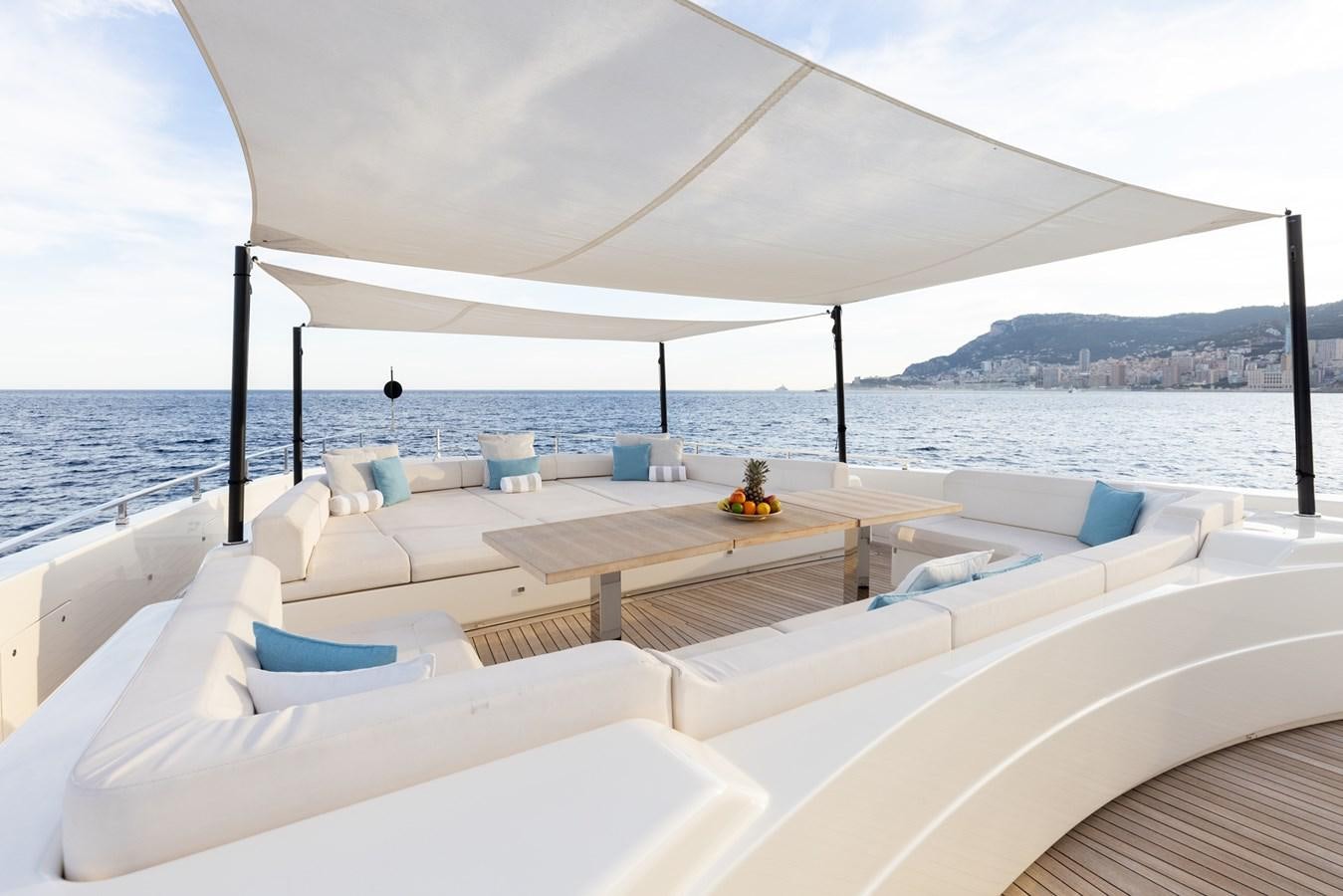 a lounge area with a large white umbrella and a table on it aboard EROS Yacht for Sale