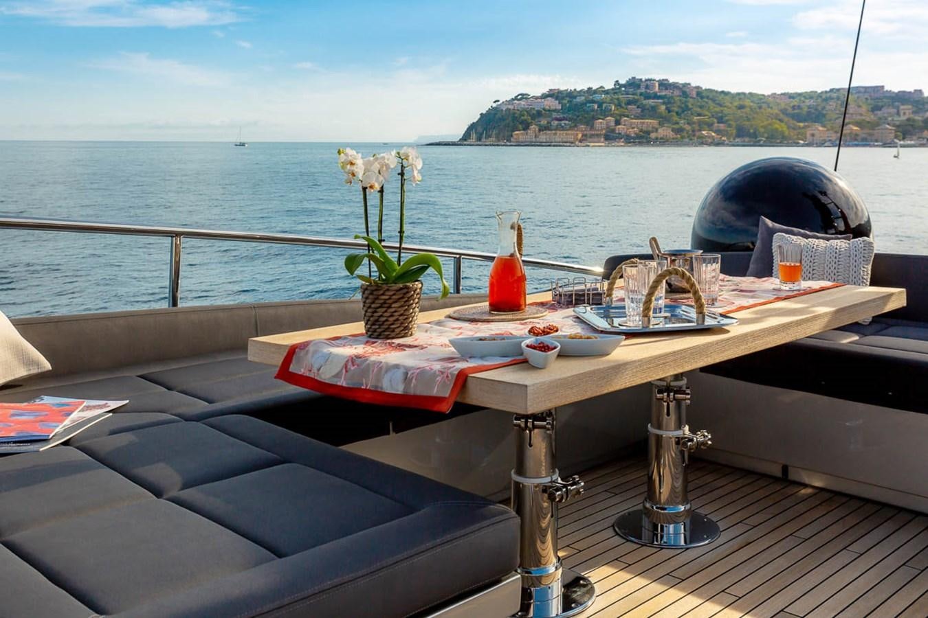 a table with a vase and flowers on it by a body of water aboard X-TREM II Yacht for Sale
